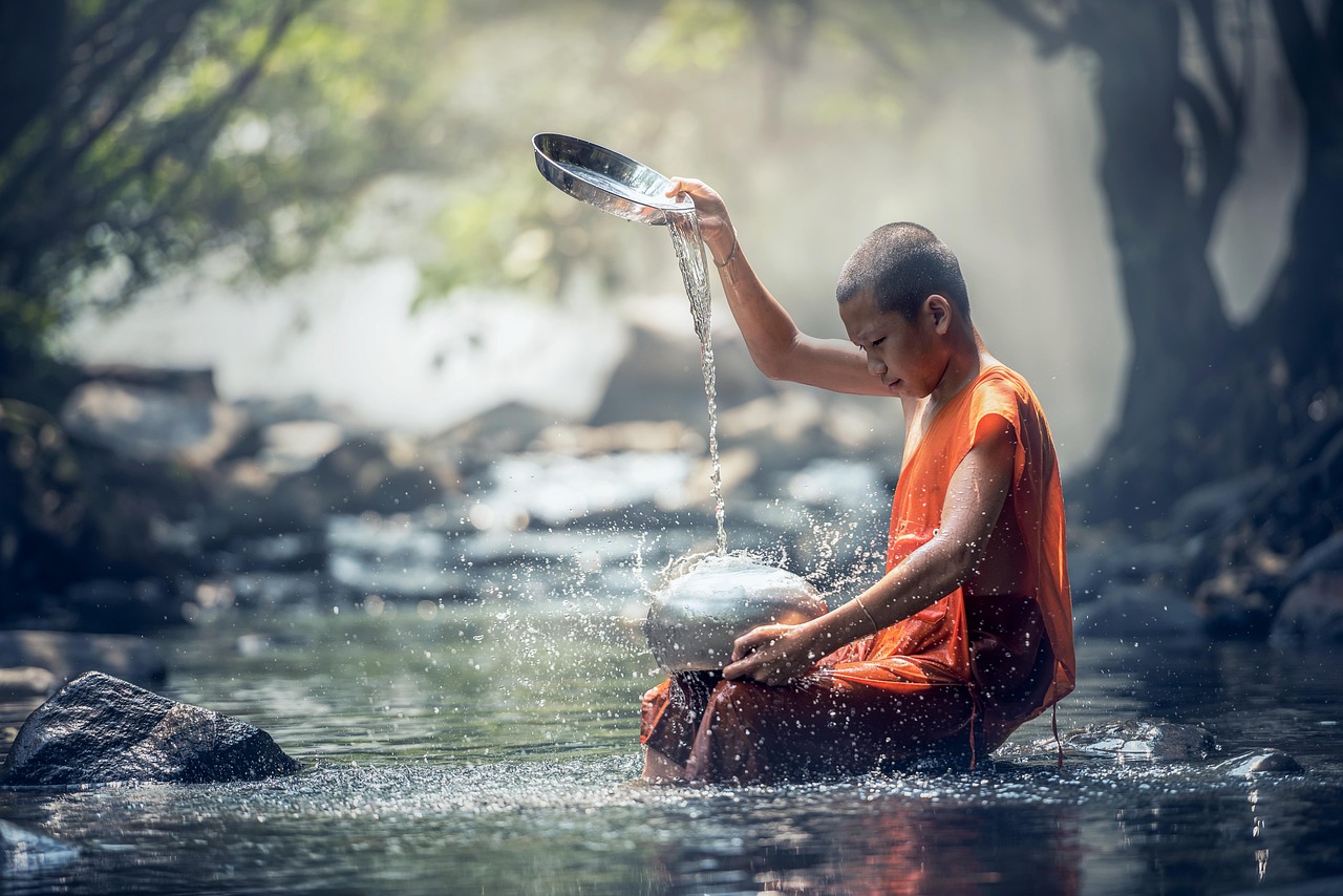Young Buddhist monk near a stream in a peaceful Thai landscape